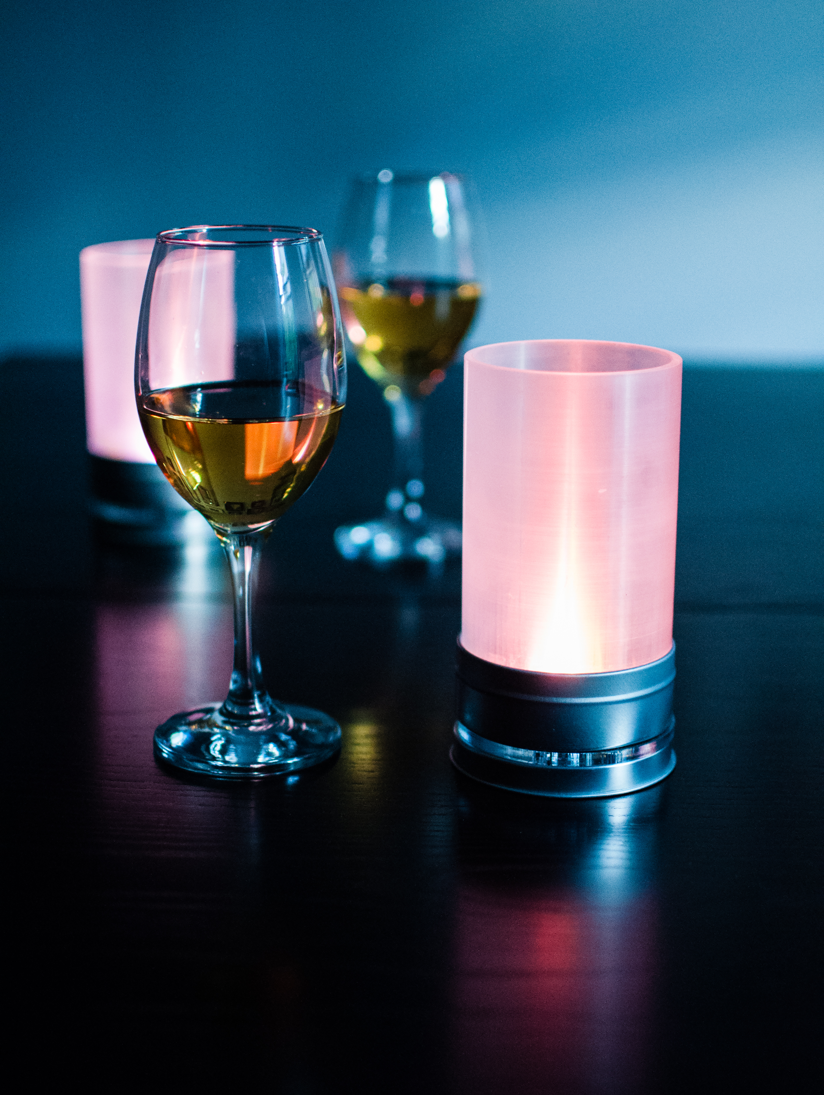 A pair of artificial candles set on a table with two glasses of wine